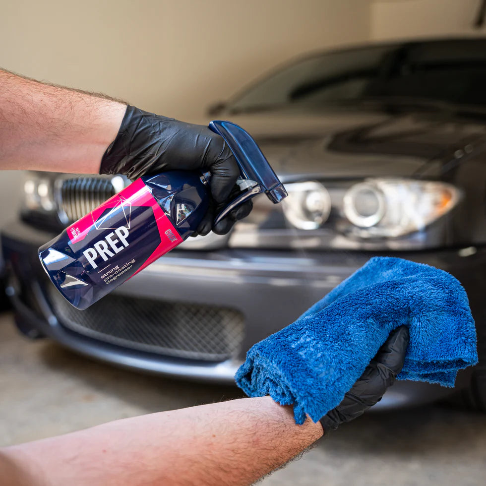 Person holding a car cleaning product Gyeon Prep and towel in front of a car