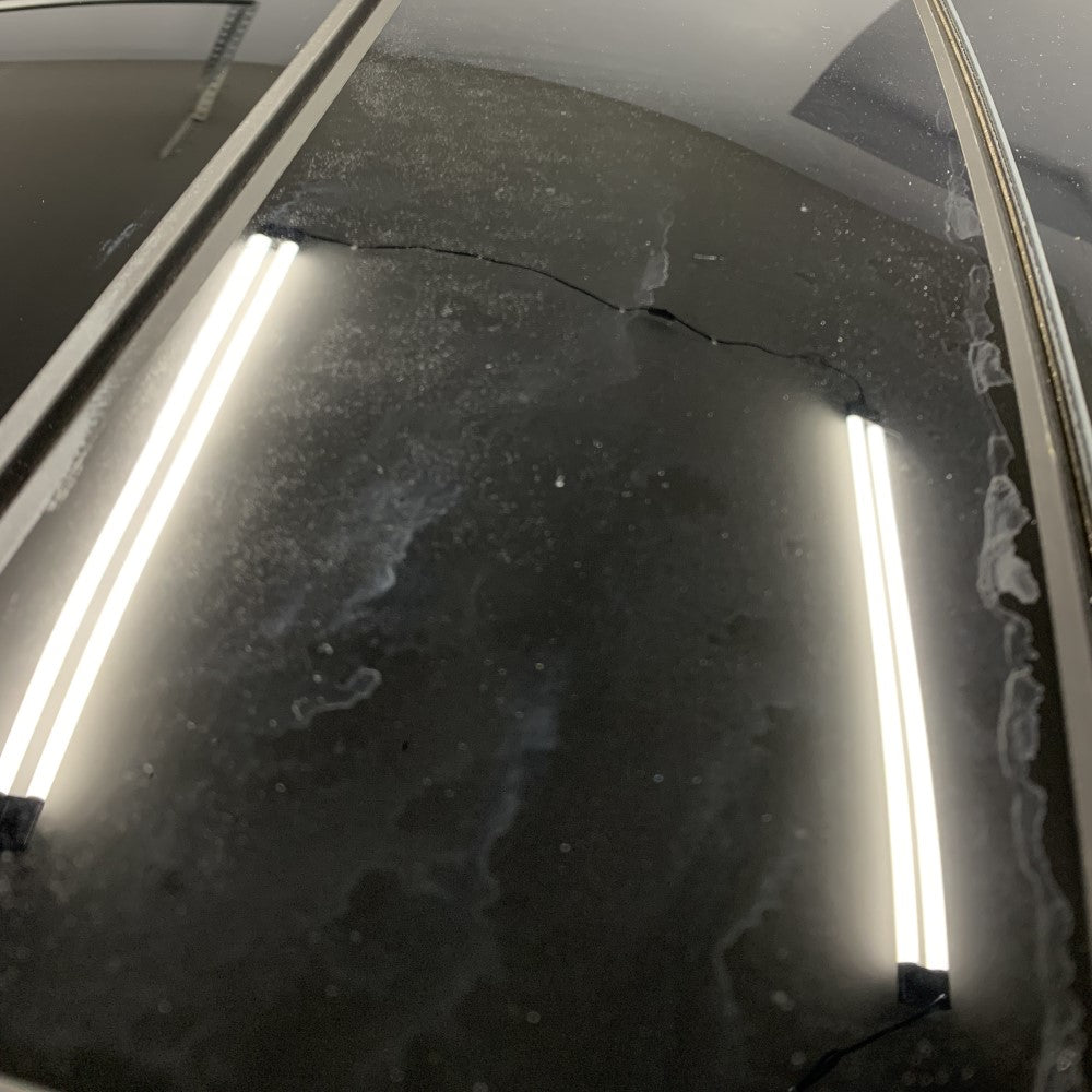 Car windshield with hard water spots, reflecting interior lights.